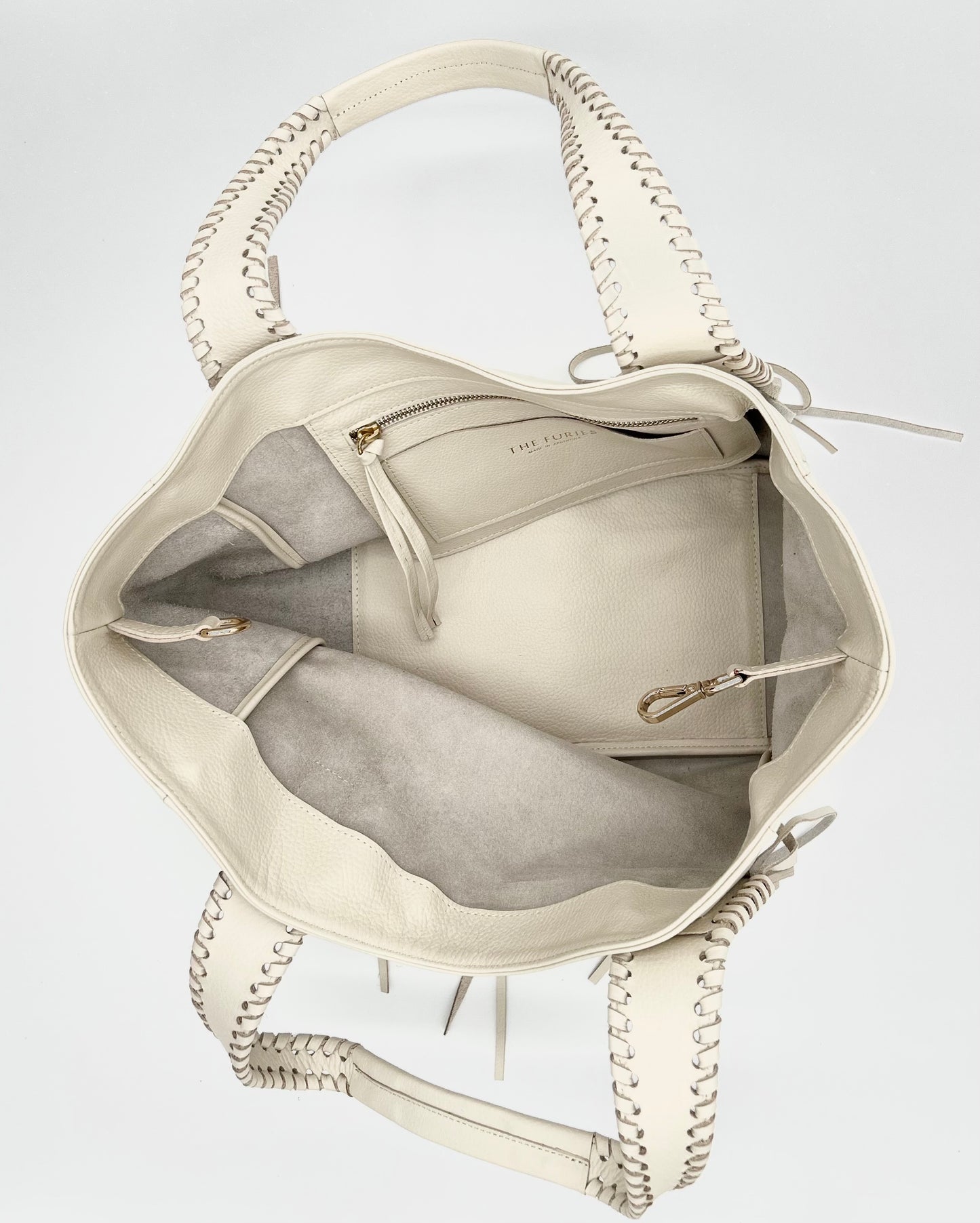 Off White Handbag with shoulder straps with whipstitching and fringe and interior pocket with zipper and a cardholder with brass hardware.