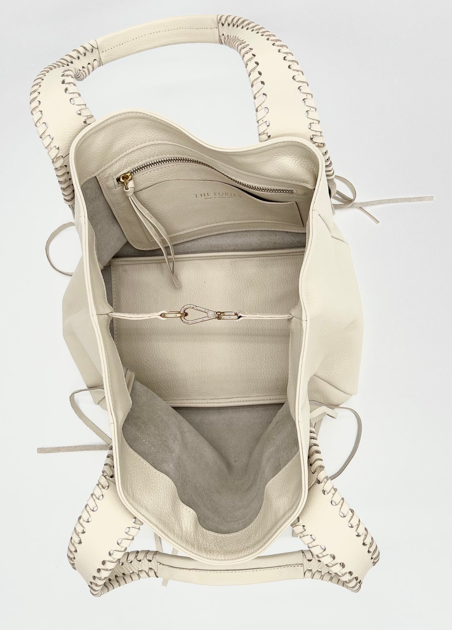 Off white handbag with whipstitched handles and fringe detail with an interior pocket with a zipper and a cardholder and brass hardware.