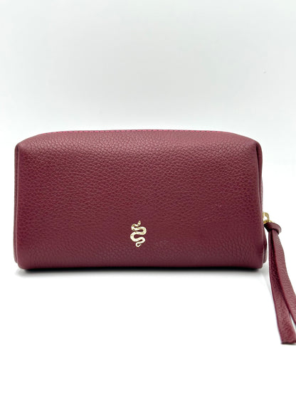 The Small Makeup Bag from The Furies Collective in Claret with a Raspberry Interior — pebble leather pouch with brass zipper for cosmetics.