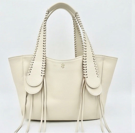 The Talitha tote handbag from The Furies Collective in Champagne — pebble leather with whipstitched fringe handles and the Furies snake logo.