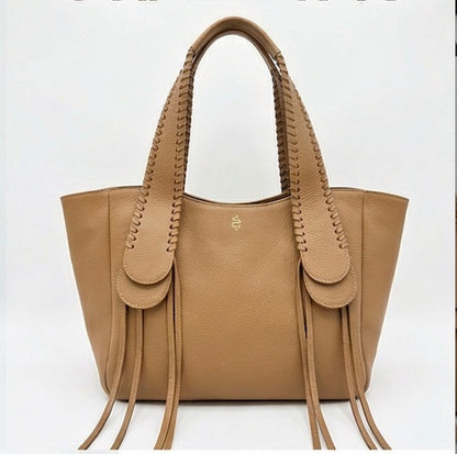 The Talitha tote handbag from The Furies Collective in Cognac — pebble leather with whipstitched fringe handles and the Furies snake logo.