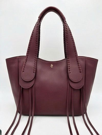 The Talitha tote handbag from The Furies Collective in Claret — pebble leather with whipstitched fringe handles and the Furies snake logo.