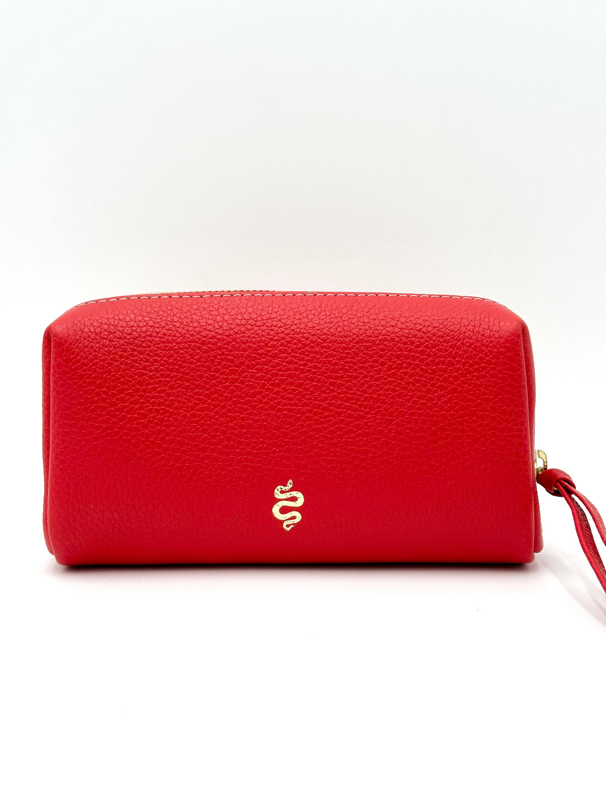 The Small Makeup Bag from The Furies Collective in Lipstick Red with a navy leather Interior — pebble leather pouch with brass zipper for cosmetics.